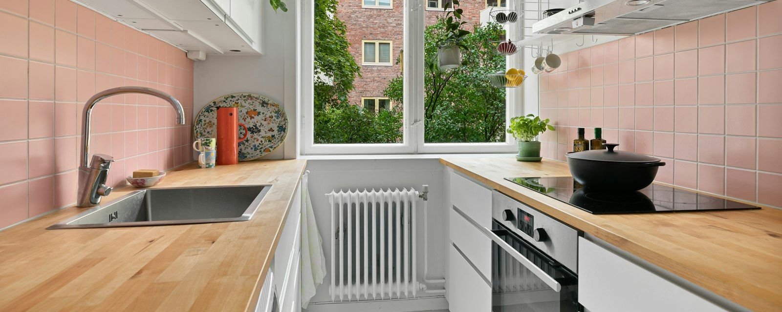 Small bright apartment kitchen with wooden counters and pink tiles